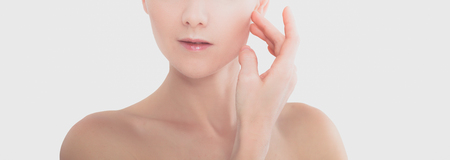 The beautiful young girl with a clean fresh skin touches with a hand a cheekの写真素材