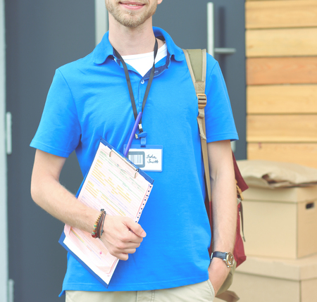 Smiling delivery man in blue uniform delivering parcel box to recipient - courier service concept. Smiling delivery man in blue uniformの写真素材