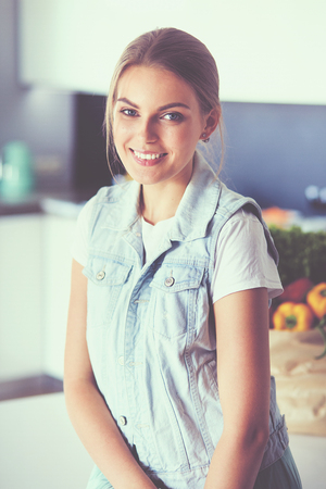Portrait of young woman standing with arms crossed against kitchen backgroundの写真素材