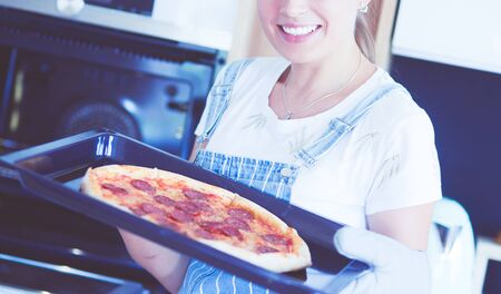 Happy young woman cooking pizza at homeの写真素材