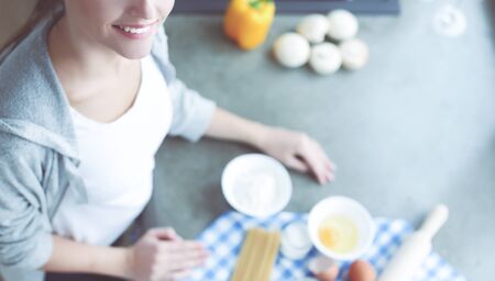 Beautiful woman cooking cake in kitchen standing near desk.の写真素材