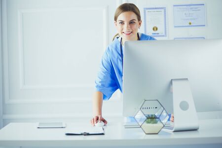 Young woman doctor at work while pointing at computer in hospital office.の写真素材