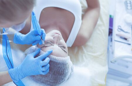 Beautiful woman face near doctor with syringe.の写真素材