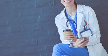 Young woman doctor sitting with your phone. Woman doctors.の写真素材