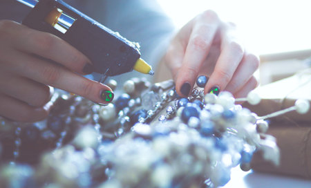 Woman preparing accessories for christmas decorations sitting on the desk.