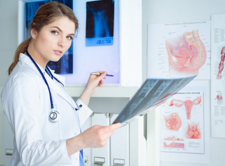 Young professional female doctor examining patients x-ray