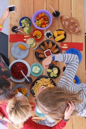 Top view of group of people having dinner together while sitting at wooden table. Food on the table. People eat fast food.の写真素材