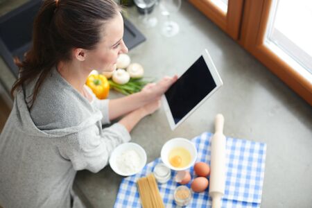 Beautiful woman cooking cake in kitchen standing near desk.の写真素材