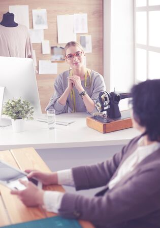 Female dressmaker is communicating with the potential client about custom-made dress in the sewing workshopの写真素材