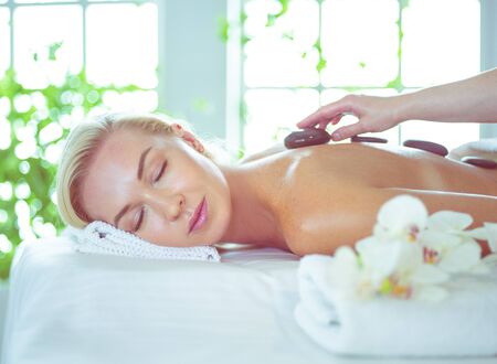 Young woman in spa salon, getting stones massageの写真素材