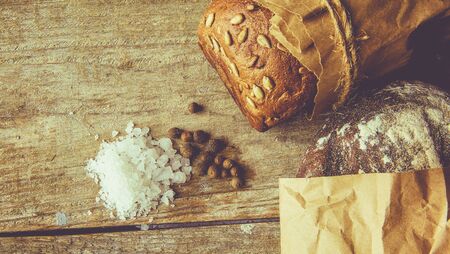 Two Loaves of Bread packed in paper on wooden tableの写真素材