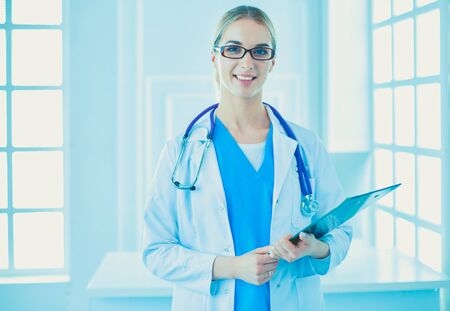 Smiling female doctor with a folder in uniform standingの写真素材