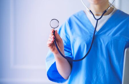 Unknown female doctor with stethoscope standing in medical officeの写真素材