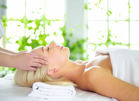 Beautiful woman doing facial massage in a spa salonの写真素材