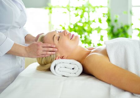 Beautiful woman doing facial massage in a spa salonの写真素材