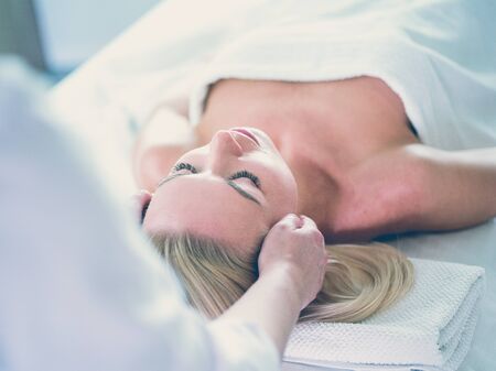 Beautiful woman doing facial massage in a spa salonの写真素材