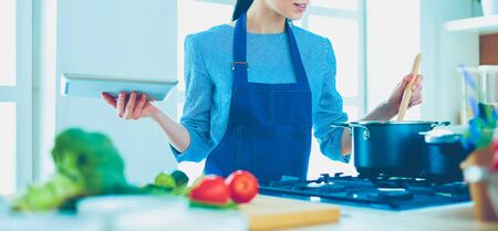 Young woman using a tablet computer to cook in her kitchenの写真素材