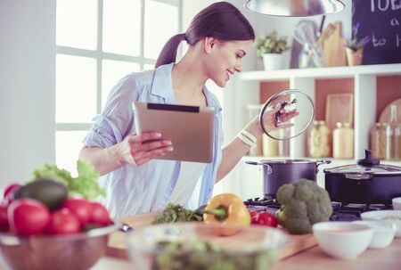Young woman standing by the stove in the kitchenの写真素材
