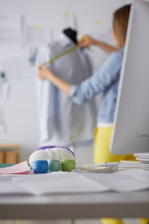 Young designer with tape is measuring white shirtの写真素材
