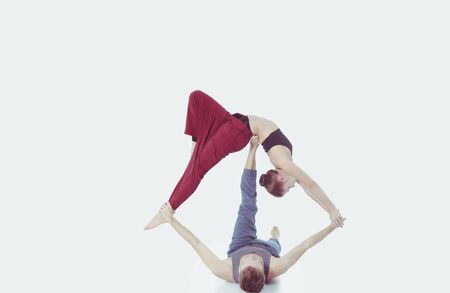 Young athletic couple practicing acroyoga. Balancing in pair.の写真素材
