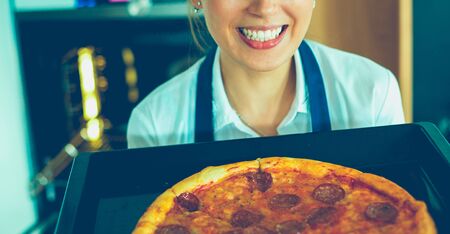 Happy young woman cooking pizza at homeの写真素材