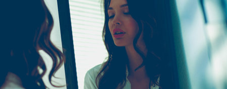 Young woman looking herself reflection in mirror at home. Young woman.