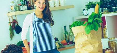 Young woman standing near desk in the kitchenの写真素材