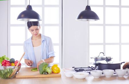 Young woman cutting vegetables in kitchen at home.の写真素材