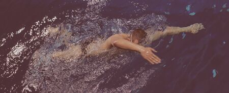 Young man swimming the front crawl in a poolの写真素材