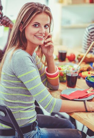 Top view of group of people having dinner together while sitting at wooden table. Food on the table. People eat fast food. The girl is talking on the phoneの写真素材