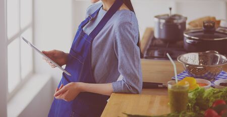 Young woman using a tablet computer to cook in her kitchenの写真素材