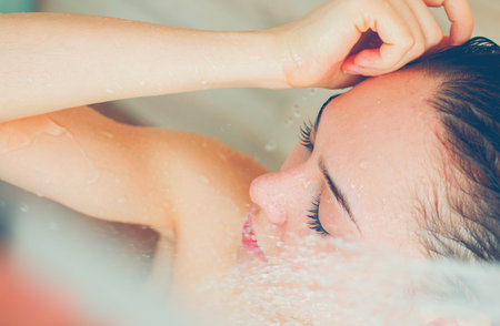 Young beautyful woman under shower in bathroom.