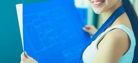 Young woman standing near desk and looking at the blueprint of new homeの写真素材