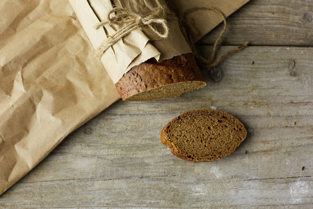 Sliced loaf of Bread packed in paper on wooden table