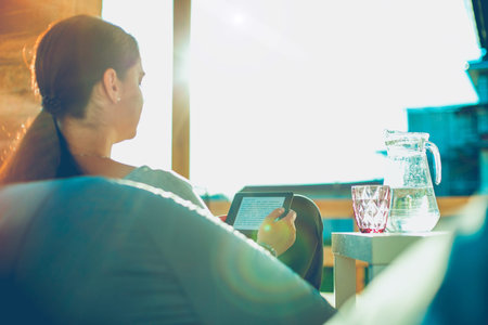 Smiling young woman sitting on sofa with touchpad.