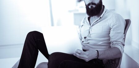 Young businessman sitting in chair over white backgroundの写真素材
