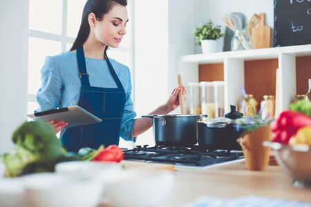 Young woman using a tablet computer to cook in her kitchenの写真素材