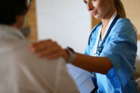 Woman doctor helping senior holding hand in hospitalの写真素材