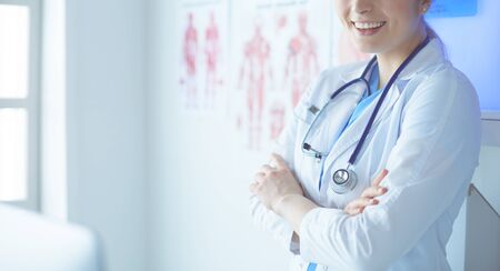 Young woman medic in white uniform standing in clinic's office.の写真素材
