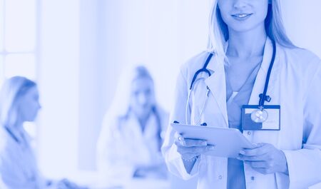 portrait of a young female doctor, with aipads in hand, in a medical office.の写真素材