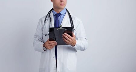 Male doctor standing with folder, isolated on white background.の写真素材