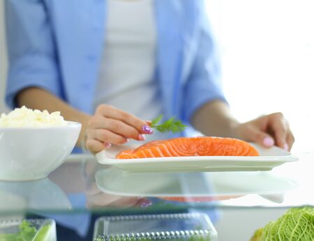 Portrait of female standing near open fridge full of healthy food, vegetables and fruitsの写真素材