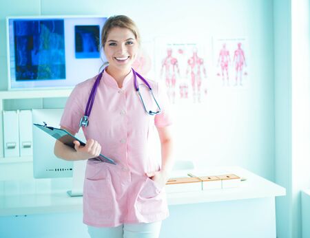 Smiling female doctor with a folder in uniform standing at hospitalの写真素材