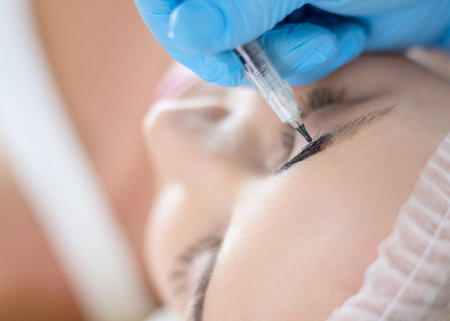 Permanent makeup for eyebrows. Closeup of beautiful woman with thick brows in beauty salon.