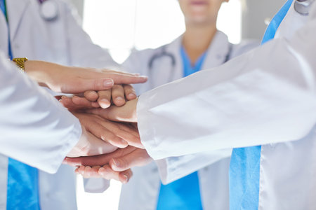 Doctors and nurses in a medical team stacking hands.
