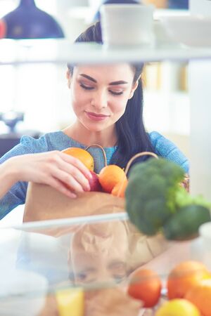 Smiling woman taking a fresh fruit out of the fridge, healthy food conceptの写真素材