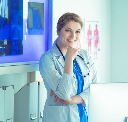 Young woman medic in white uniform standing in clinics officeの写真素材