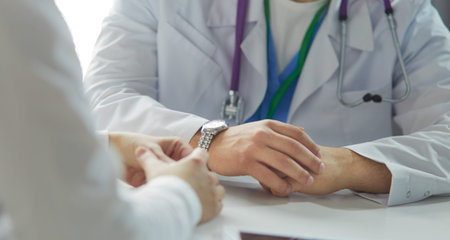 Portrait of a male doctor with laptop sitting at desk in medical office.