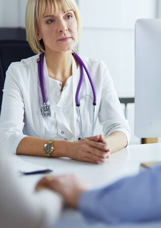 Female doctor sitting on the desk and working a laptop in hospilの写真素材