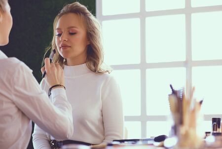 make up artist doing professional make up of young womanの写真素材
